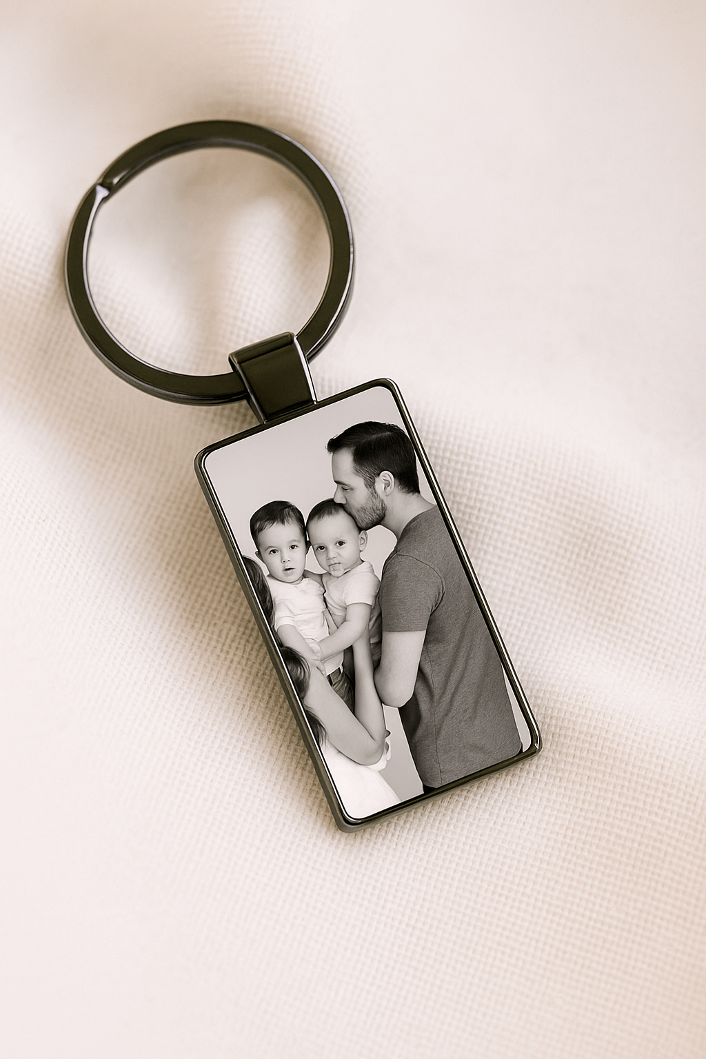 Custom keychain with a black and white photo of a father kissing a toddler while holding a second child, symbolizing love and family moments. Made by Your iDeas Shop.