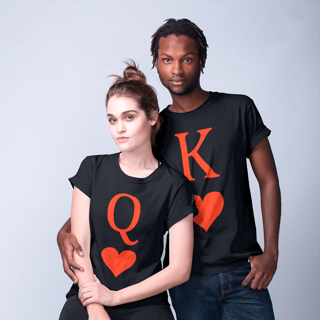 Stylish interracial couple in a studio setting wearing coordinating black shirts: hers displays a large red ‘Q’ above a heart symbol, his features a bold red ‘K’ and matching heart. A minimalist matching outfit for romantic partners and playing-card lovers. Made by Your iDeas Shop.