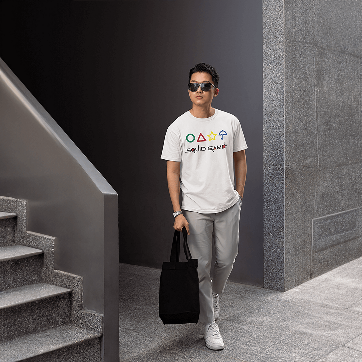 A fashionable man dressed in a white 'Squid Game' T-shirt featuring series-inspired graphics, walking confidently with a black tote bag. Ideal for urban style showcases. Made by Your iDeas Shop.