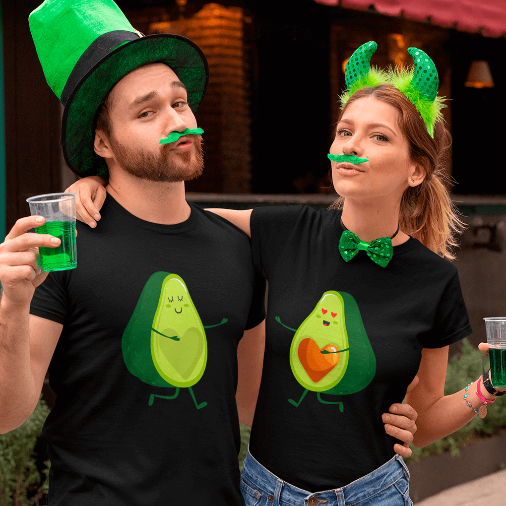Two people wearing black t-shirts with avocado designs, green hats, and holding drinks.