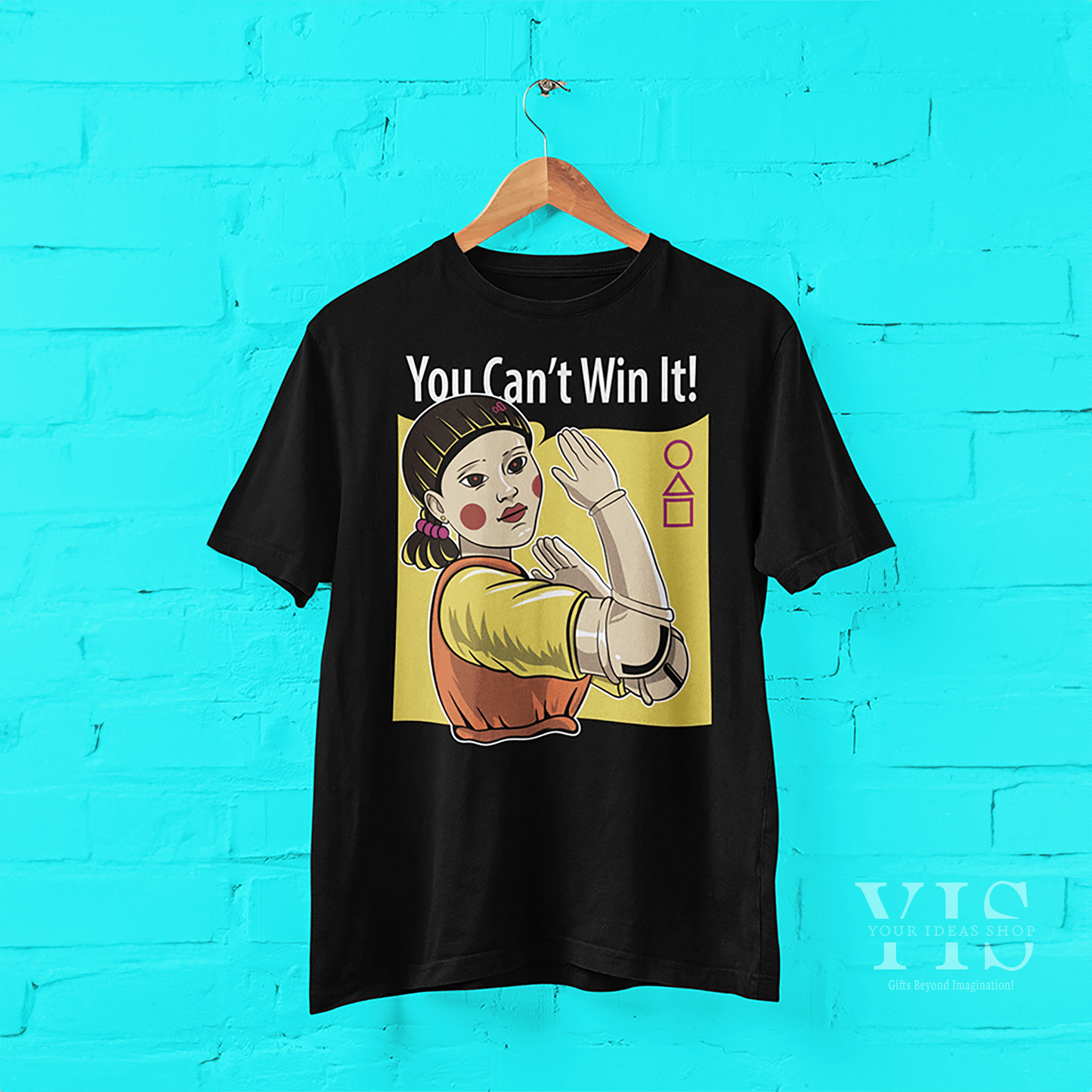 A black T-shirt hanging against a bright backdrop, featuring the 'Red Light, Green Light' doll with a yellow background and playful text. A unique and bold addition to any casual wardrobe. Made by Your iDeas Shop.