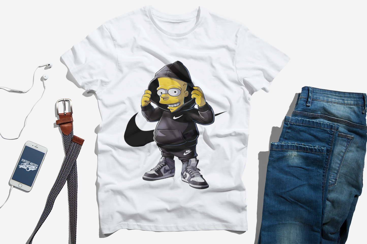 Flat lay of a white t-shirt featuring a cartoon character resembling Bart Simpson in a black hoodie, paired with men's accessories including a belt, a smartphone, and blue jeans, arranged on a white background for a casual and stylish outfit look.