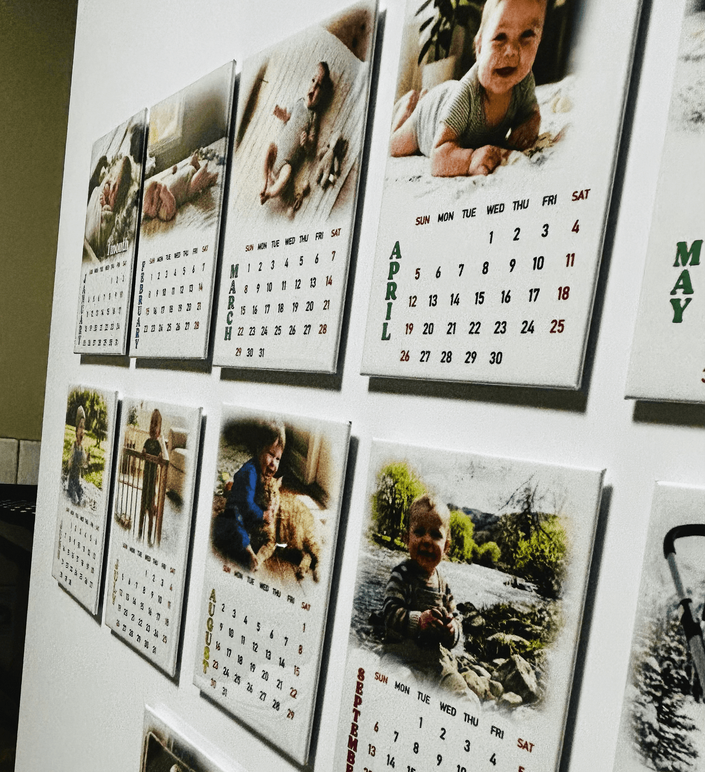 Personalized 12-month photo magnet calendar set showcasing monthly pictures of babies and family moments on a wall.