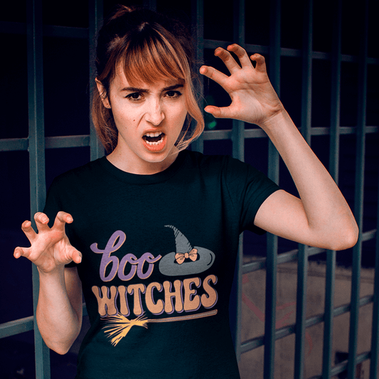 Woman wearing a black t-shirt with 'boo WITCHES' design, standing in front of a dark background.