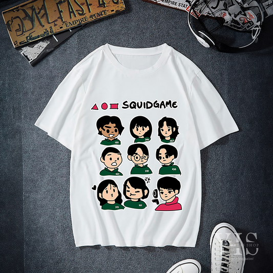 A white T-shirt featuring a cartoon-style graphic of Squid Game characters. The design includes colorful character faces arranged in a grid with recognizable shapes and the text 'Squid Game' at the top. A playful and stylish design for fans of the series. Made by Your iDeas Shop.