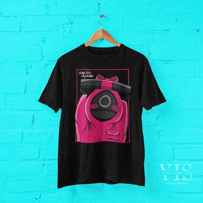 A sleek black T-shirt showcasing a cartoon design of a pink-suited guard holding a bow-tied gift box. The bold pink frame and 'Squid Game' text complete this trendy and creative design. Ideal for casual outfits or fan memorabilia. Made by Your iDeas Shop.