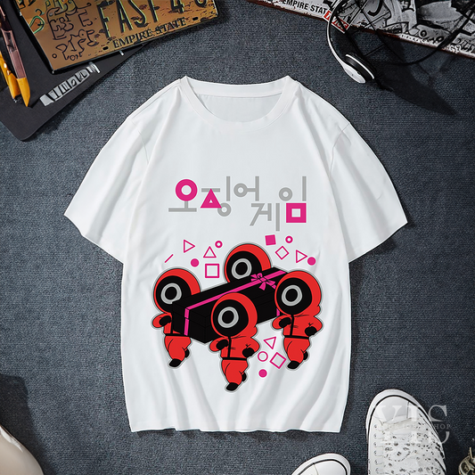 A white T-shirt featuring a playful design of red-suited guards carrying a black gift box wrapped in a pink ribbon. The design is surrounded by geometric shapes and includes Korean text above. A fun and stylish choice for fans of creative designs. Made by Your iDeas Shop