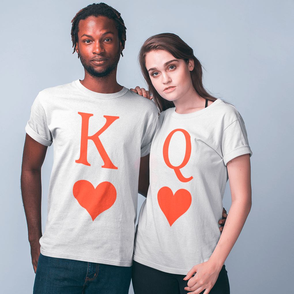Couple standing side by side in crisp white matching T-shirts; the man’s shirt shows an orange-red ‘K’ with a heart beneath, while the woman’s displays the complementary ‘Q’ with identical heart graphic, creating a balanced king-and-queen theme perfect for engagements, weddings or Valentine’s gifts. Made by Your iDeas Shop.