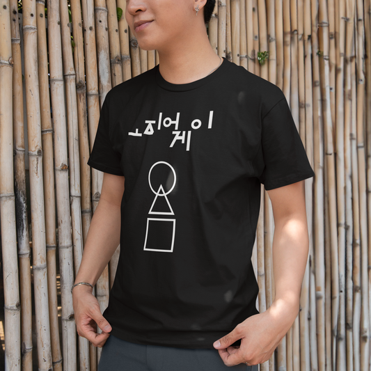 A man standing by a bamboo wall wearing a black 'Squid Game' T-shirt, featuring white minimalist geometric shapes and Korean text. A sleek and modern design for fans of the series. Made by Your iDeas Shop.