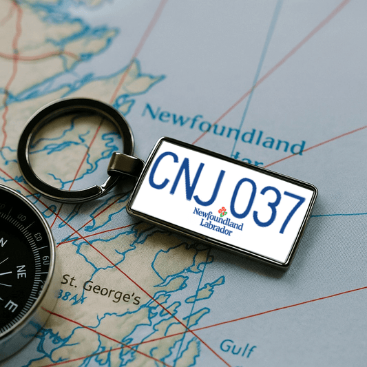 A rectangular metal keychain designed like a Newfoundland and Labrador license plate with the code 'CNJ 037', placed on a regional map near the area marked 'St. George’s'. A compass is visible to the side, enhancing the travel and navigation theme. Perfect as a Canadian souvenir for adventurers. Made by Your iDeas Shop