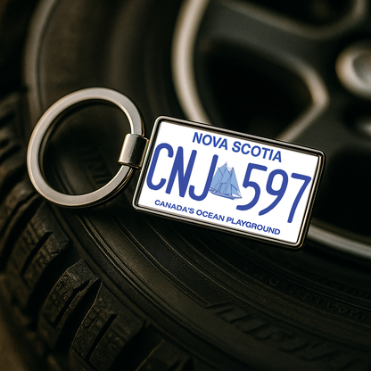 A metal keychain shaped like a Nova Scotia license plate with the number CNJ 597, placed on a car tire with a wheel rim in the background. Perfect for car enthusiasts or as a unique automotive gift. Made by Your iDeas Shop.