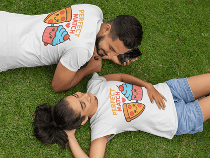 Man and woman relaxing on green grass in coordinated white tees printed with the phrase ‘Perfect Match’ above kawaii pizza and cupcake characters, capturing a playful picnic scene and ideal for romantic gift ideas. Made by Your iDeas Shop