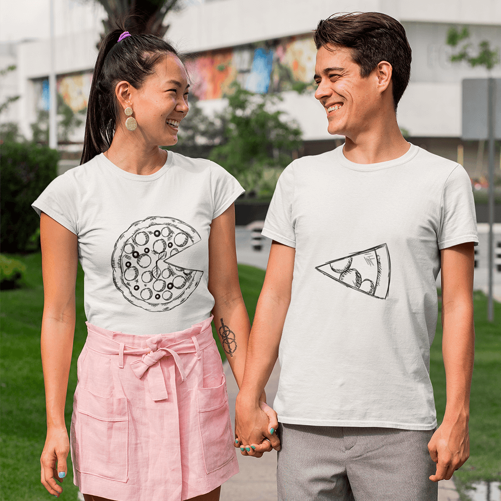 Two people holding hands, wearing matching t-shirts with pizza designs outdoors.