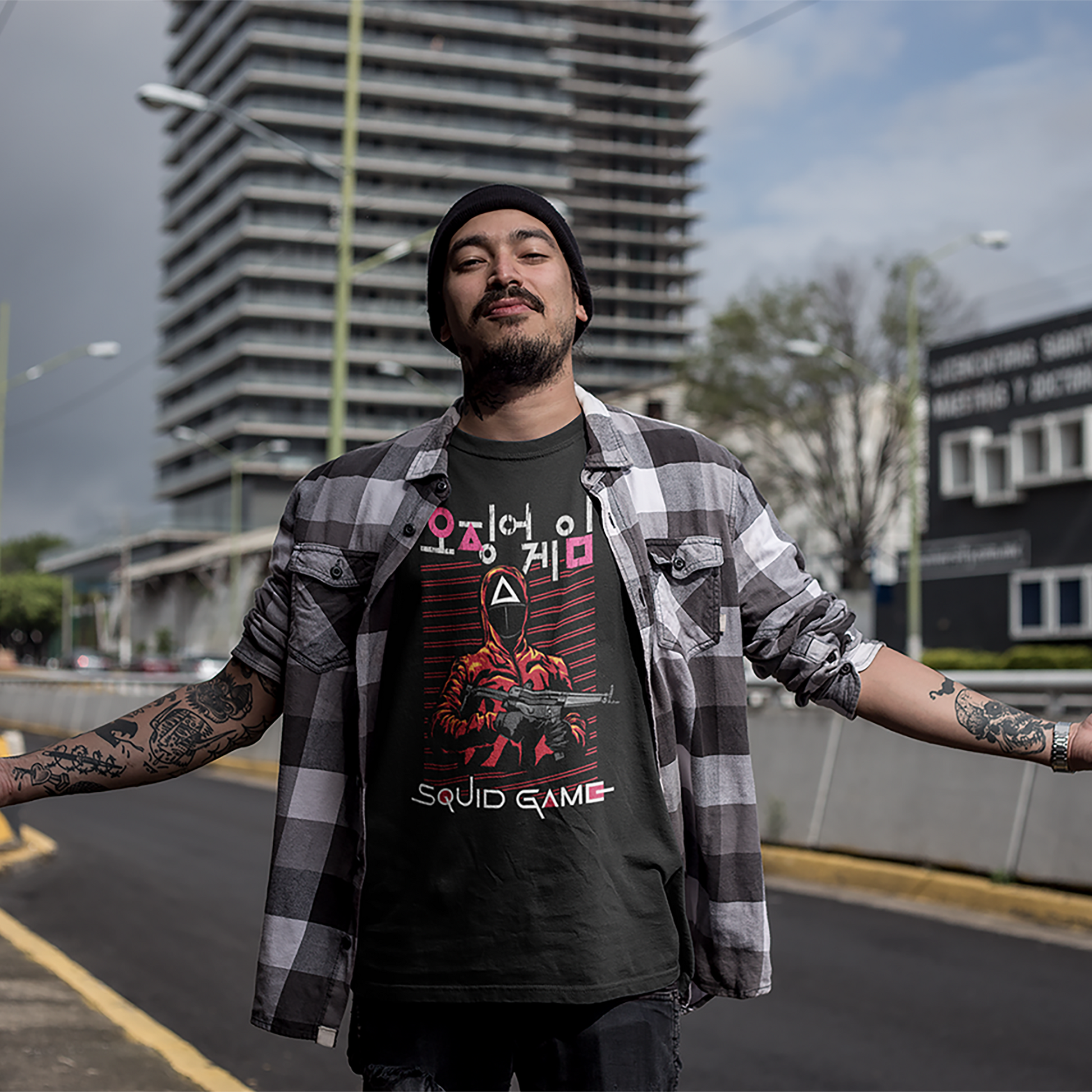 A streetwear-inspired mockup of a man wearing a 'Squid Game' T-shirt, featuring the series' signature masked guard and bold text design, set against a cityscape backdrop. Ideal for urban fashion promotions. Made by Your iDeas Shop.