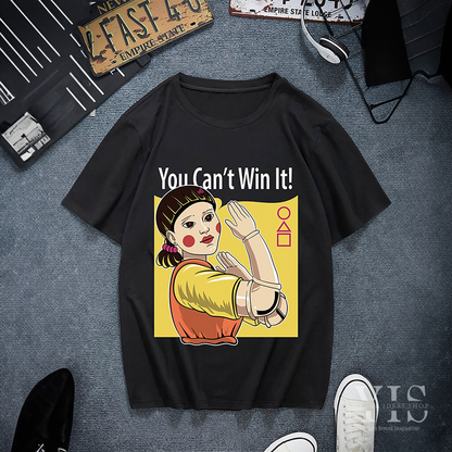 A black T-shirt featuring the iconic 'Red Light, Green Light' doll from Squid Game with the bold text 'You Can't Win It!' in white. The graphic includes a yellow backdrop and geometric symbols, creating a striking and playful design. Made by Your iDeas Shop.