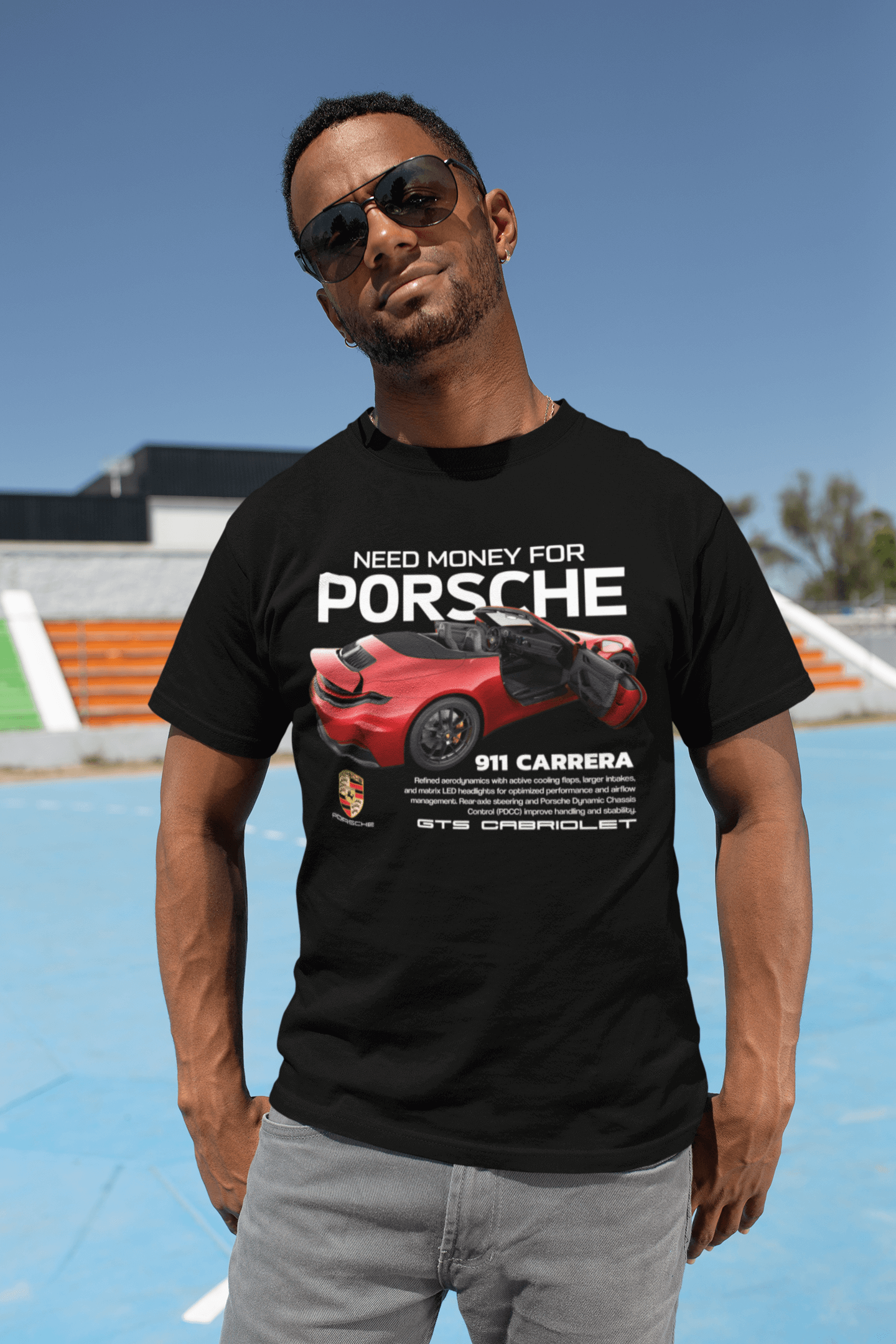 Man wearing Need Money For Porsche 911 Carrera GTS Cabriolet graphic t-shirt in black, standing outdoors.